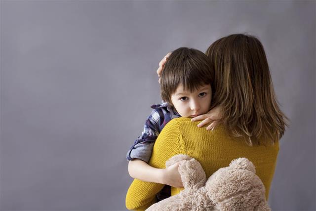 Sad little child boy hugging his mother at home
