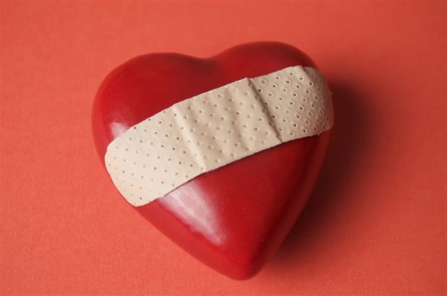 Three-dimensional heart with Band-Aid on red surface
