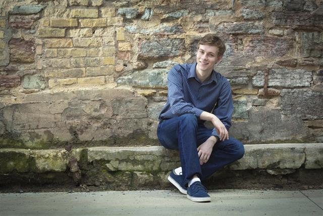 Urban Young Man Sitting Against Brick and Stone Wall