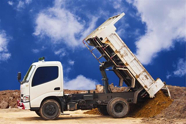 Dumper truck unloading soil or sand at construction site