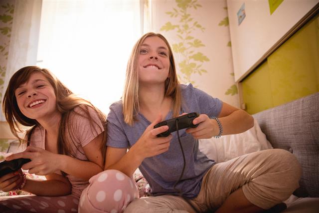 Girl jokingly pushing her friend while playing computer games
