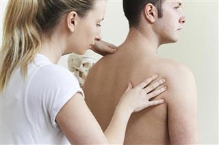 Female Osteopath Treating Male Patient With Shoulder Problem