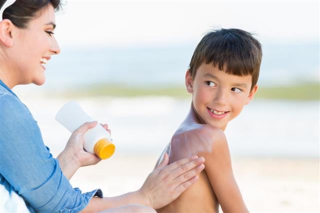 Mom puts sunscreen on son on the beach