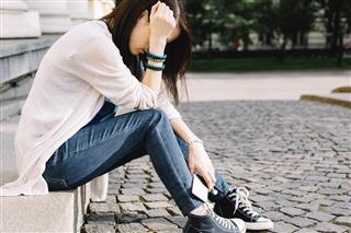 Depressed girl sitting at the street