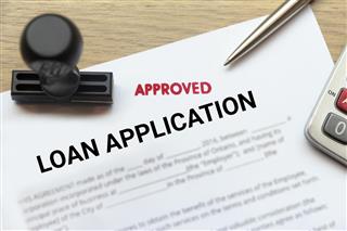Approved loan application form lay down on desk with stamp