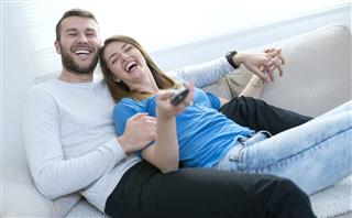 Smiling Couple at Home Watching tv and Lying on Sofa