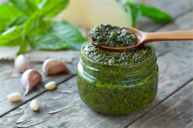 Gourmet traditional Italian pesto in glass jar with wooden spoon