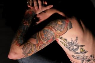 Tattooed youth holding head in his hands