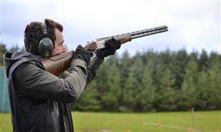 Man shooting shotguns at clay pigeon outdoors