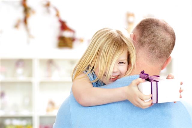 Father carrying happy daughter holding gift box