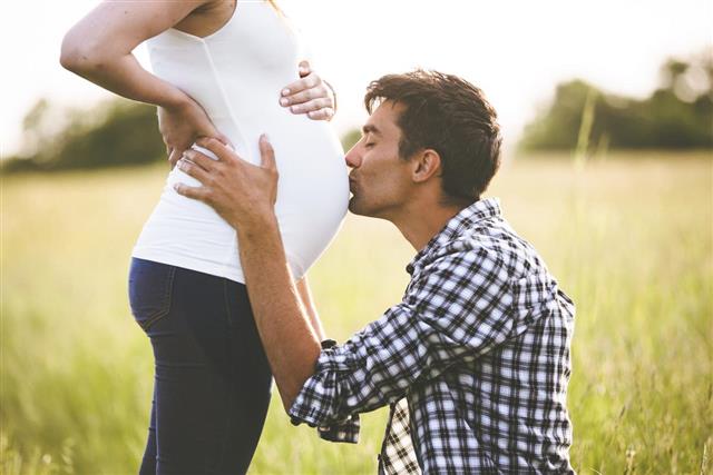 Young man kissing the belly of his pregnant woman