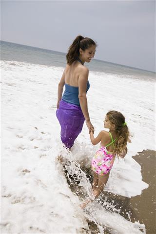 Mother And Daughter Walking Through Surf