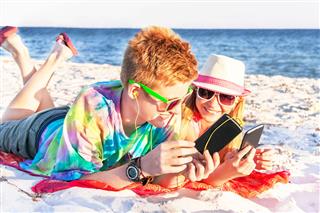 Teenagers Using Smart Phone On Beach