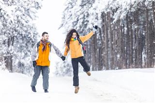 Cheerful Tourists Jumping In Snow Forest