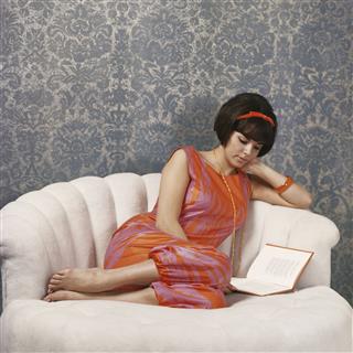 Young Woman Reading Book On Sofa